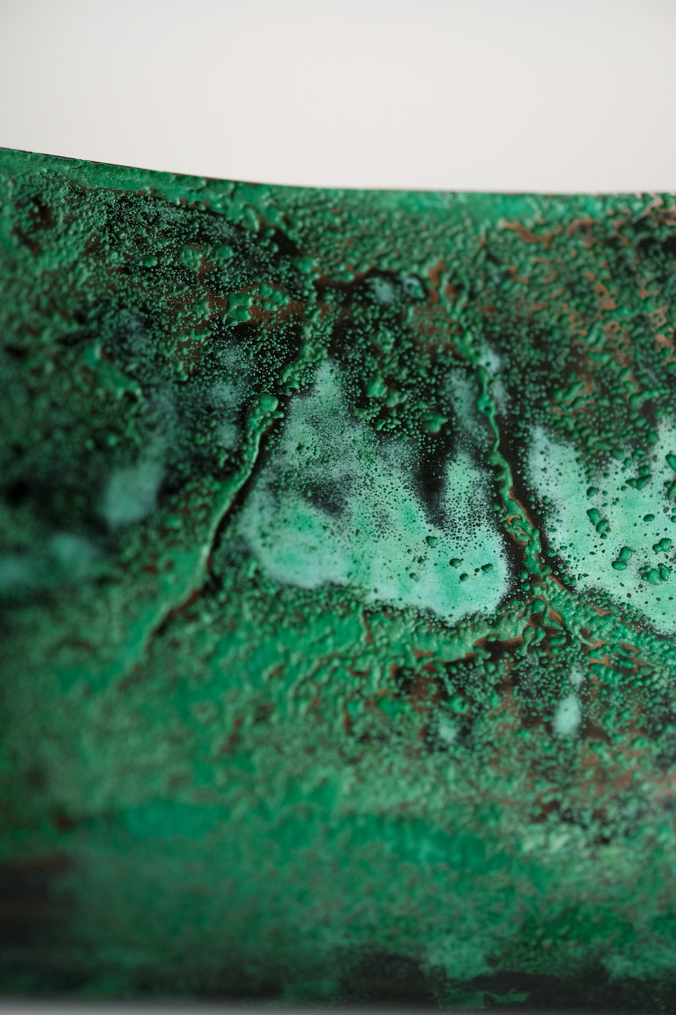 Close-up of a green patinated surface, its mineral crust broken by copper and pale bloom.